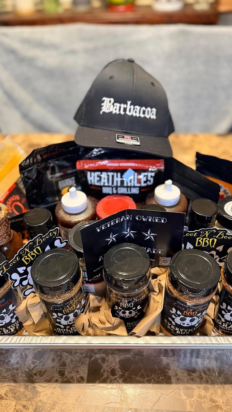 BBQ gift basket with seasoning rubs, sauces, and a black Barbacoa baseball cap.