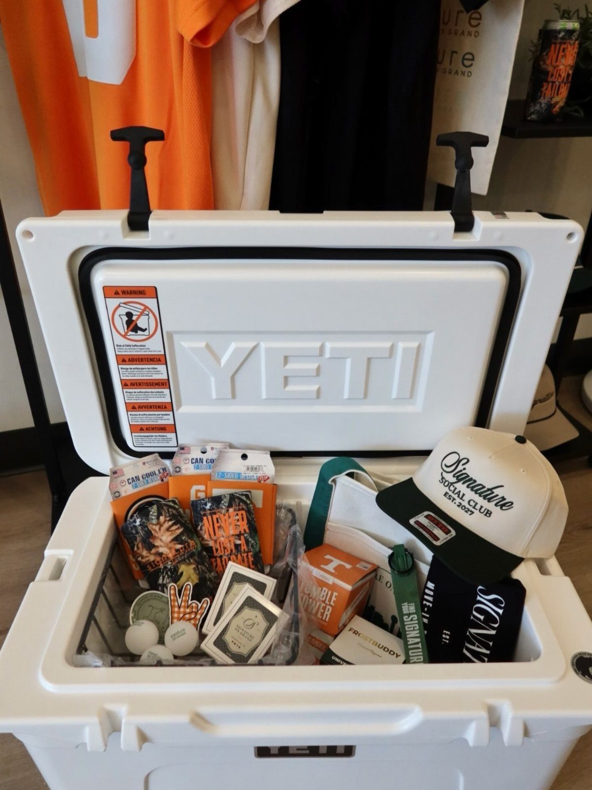 White Yeti cooler filled with a baseball cap, snacks, and sports merchandise.