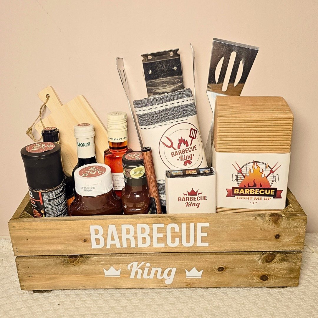 Barbecue gift crate containing grilling tools, sauces, and spices for outdoor cooking.