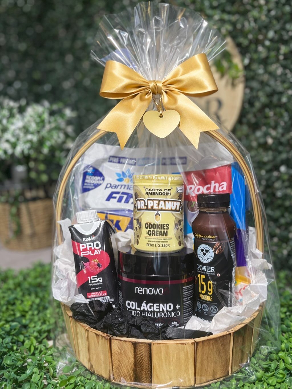 Wicker gift basket filled with protein supplements and health foods wrapped in cellophane.
