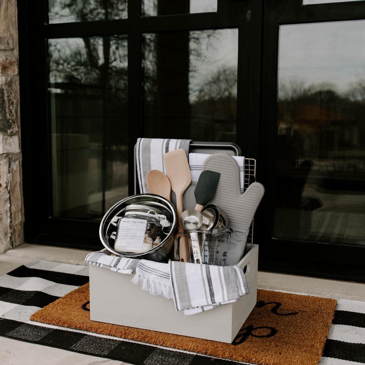 Kitchen-themed gift basket in a white wooden crate with cooking utensils and towels.