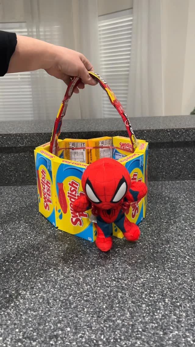 Candy box basket filled with treats and a small Spider-Man plush toy.