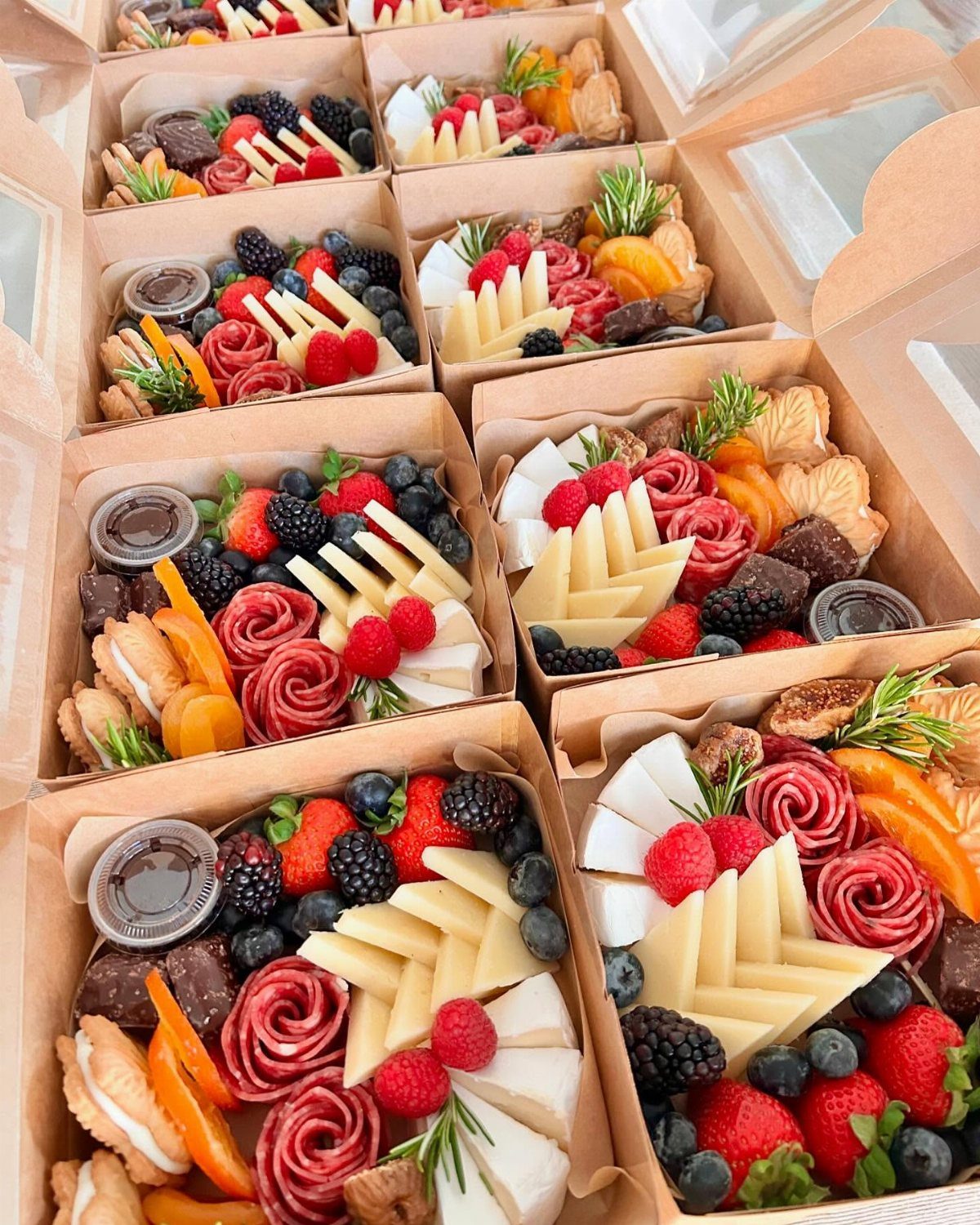 Charcuterie boxes filled with assorted cheeses, cured meats, fresh berries, and crackers.