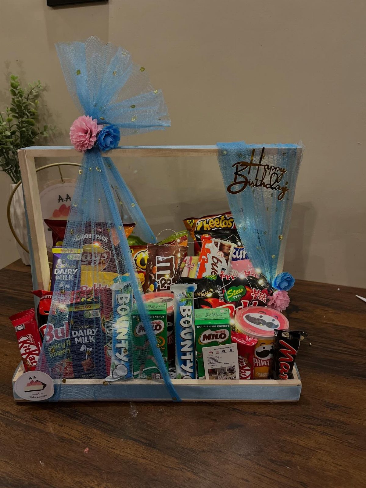 Candy gift basket in a white wooden crate with a blue ribbon bow.
