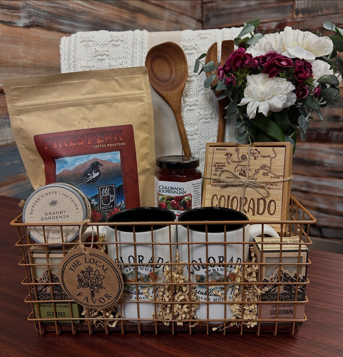 Colorado-themed gift basket with local coffee, jam, mugs, and wooden decor in wire basket.