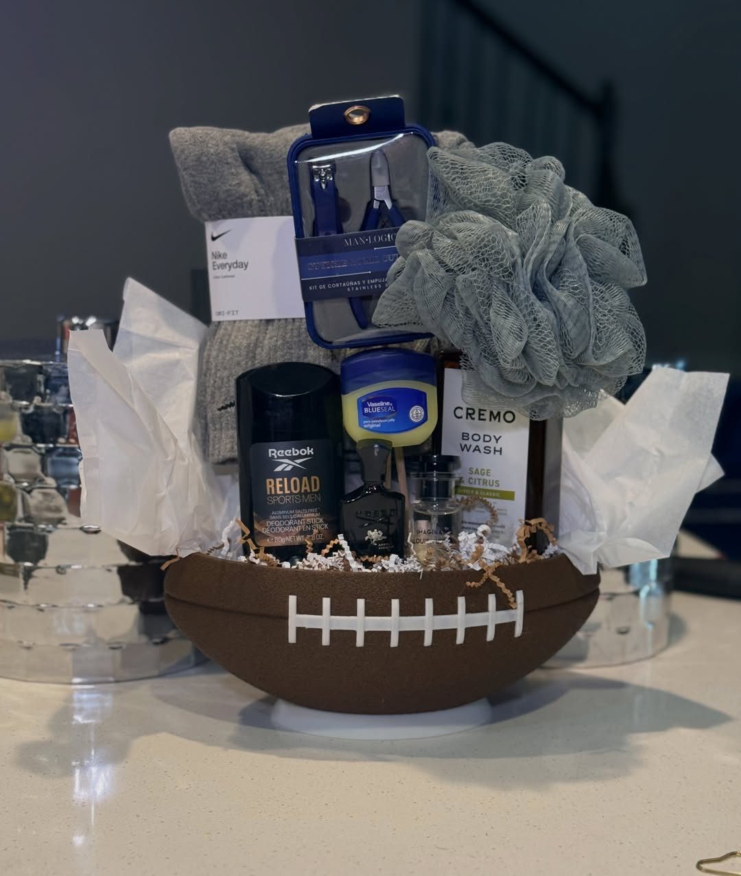 Football shaped gift basket filled with men's grooming products and grey Nike socks.
