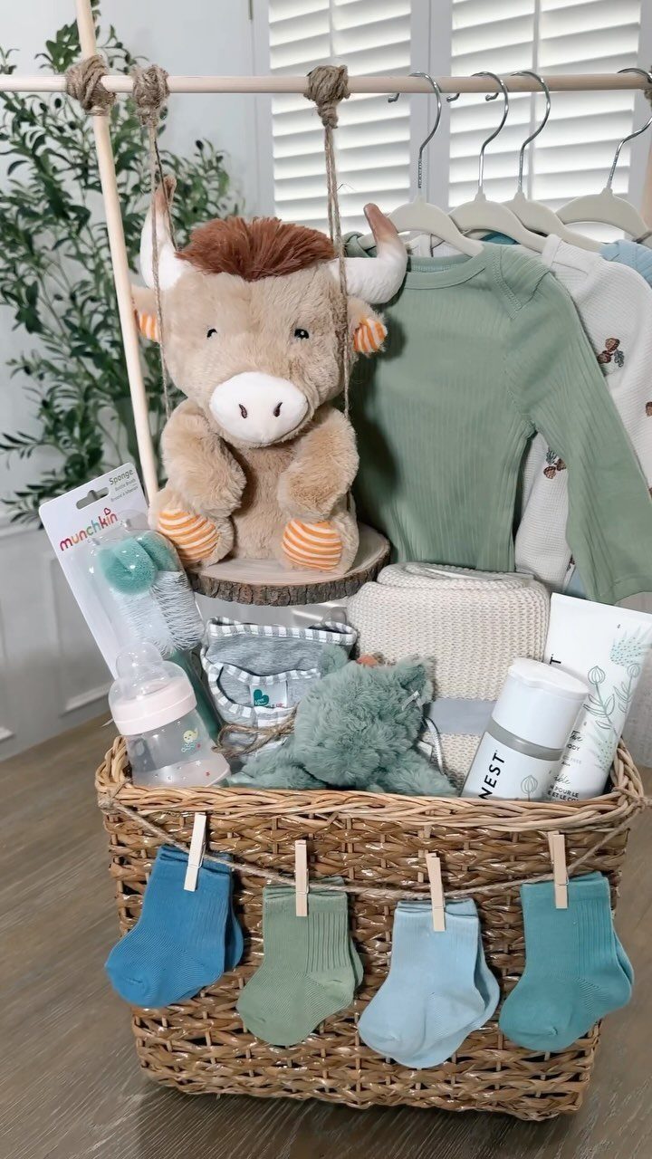 Woven gift basket filled with baby clothes, a plush bison, and blue socks.