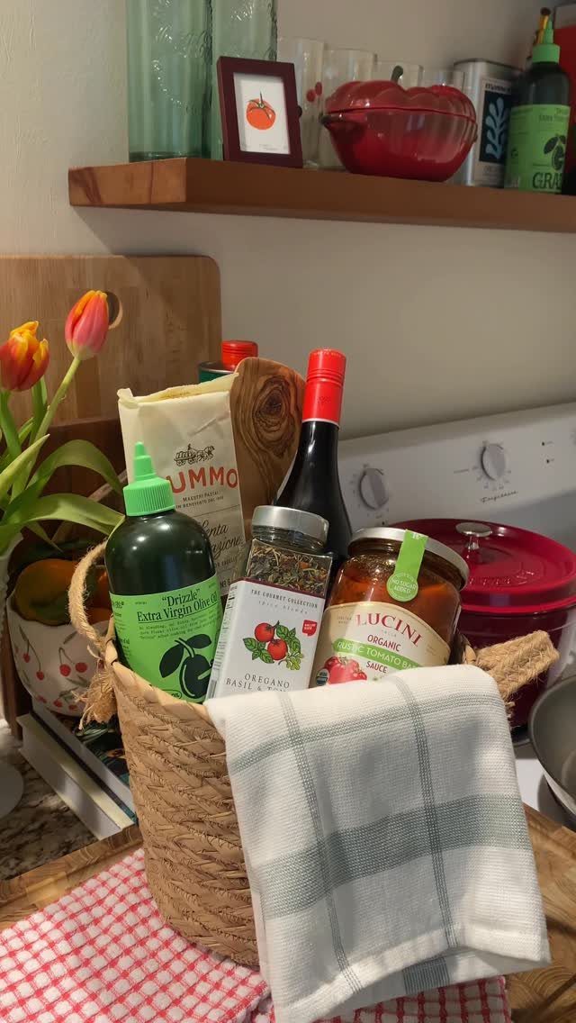 Woven gift basket filled with pasta, pasta sauce, olive oil, and balsamic vinegar.