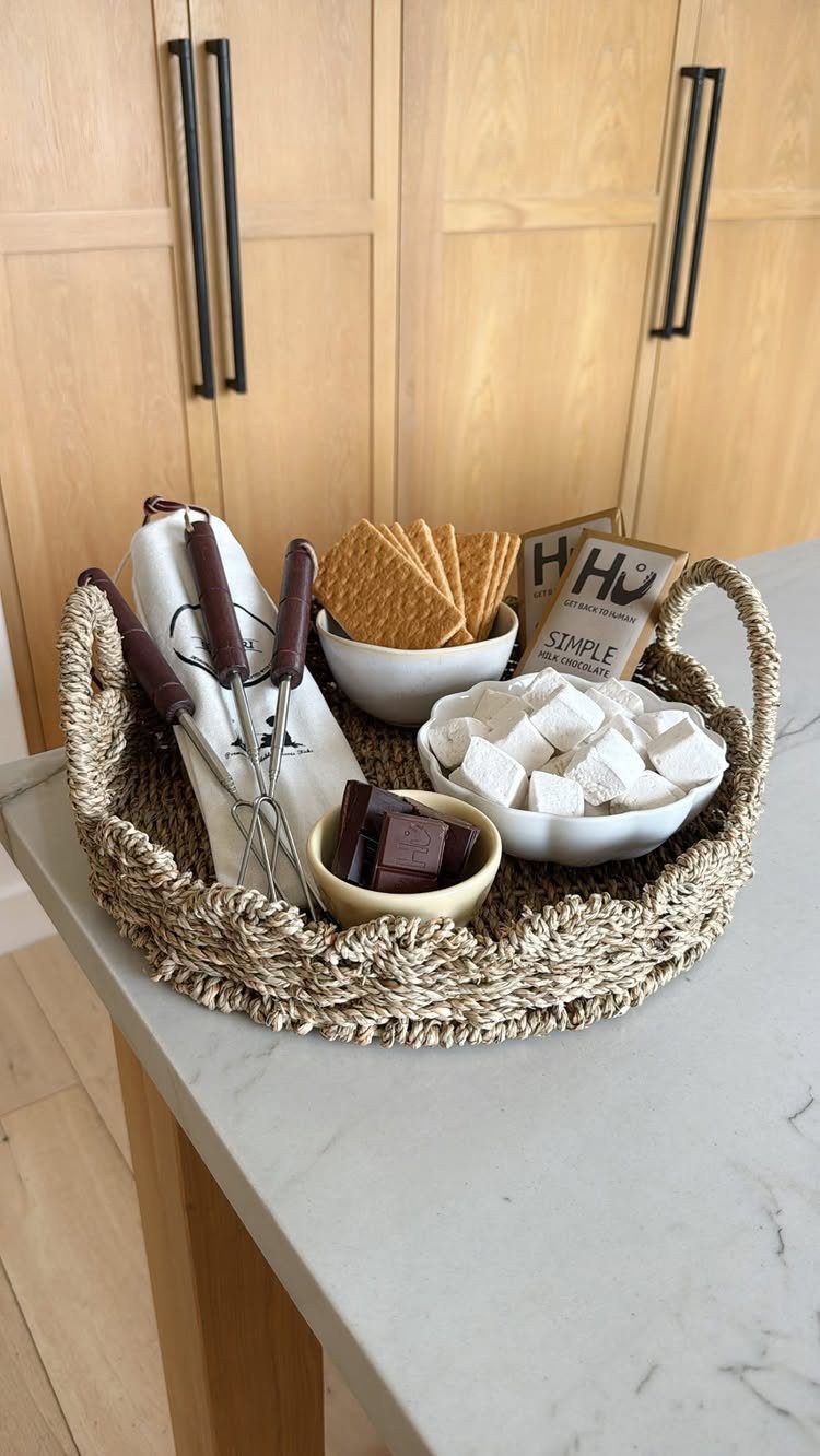 S'mores kit in a woven basket with marshmallows, chocolate, crackers, and roasting sticks.