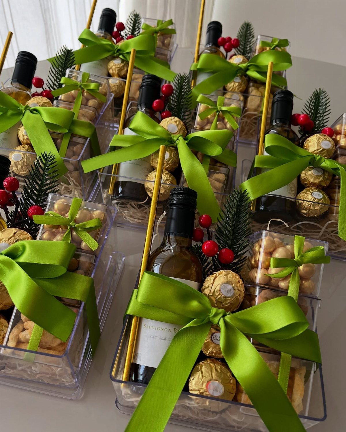 Wine gift baskets with green bows, small wine bottles, and gold chocolates.