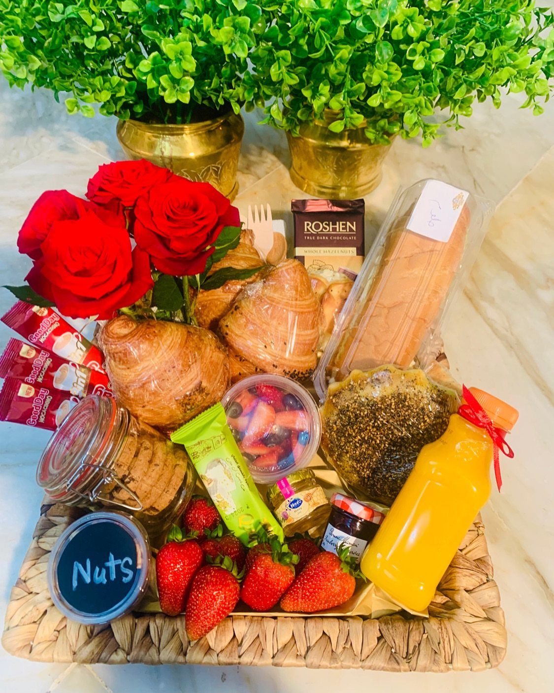 Breakfast gift basket with croissants, strawberries, orange juice, and red roses.