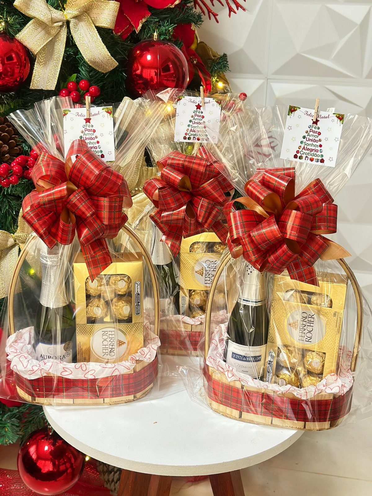 Three mini wine gift baskets with sparkling wine and chocolates wrapped in cellophane.