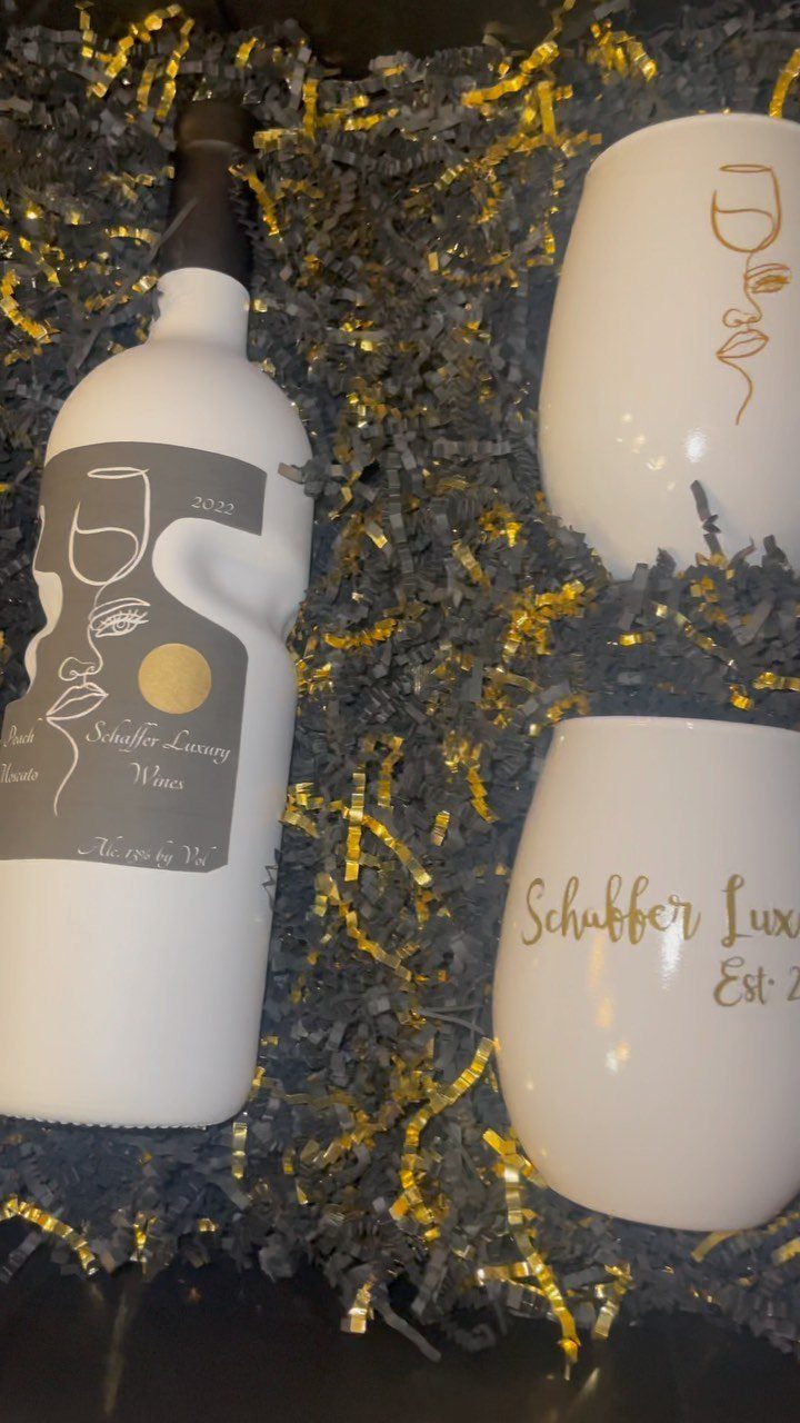 White wine bottle and two stemless glasses in a gold and grey filler box.