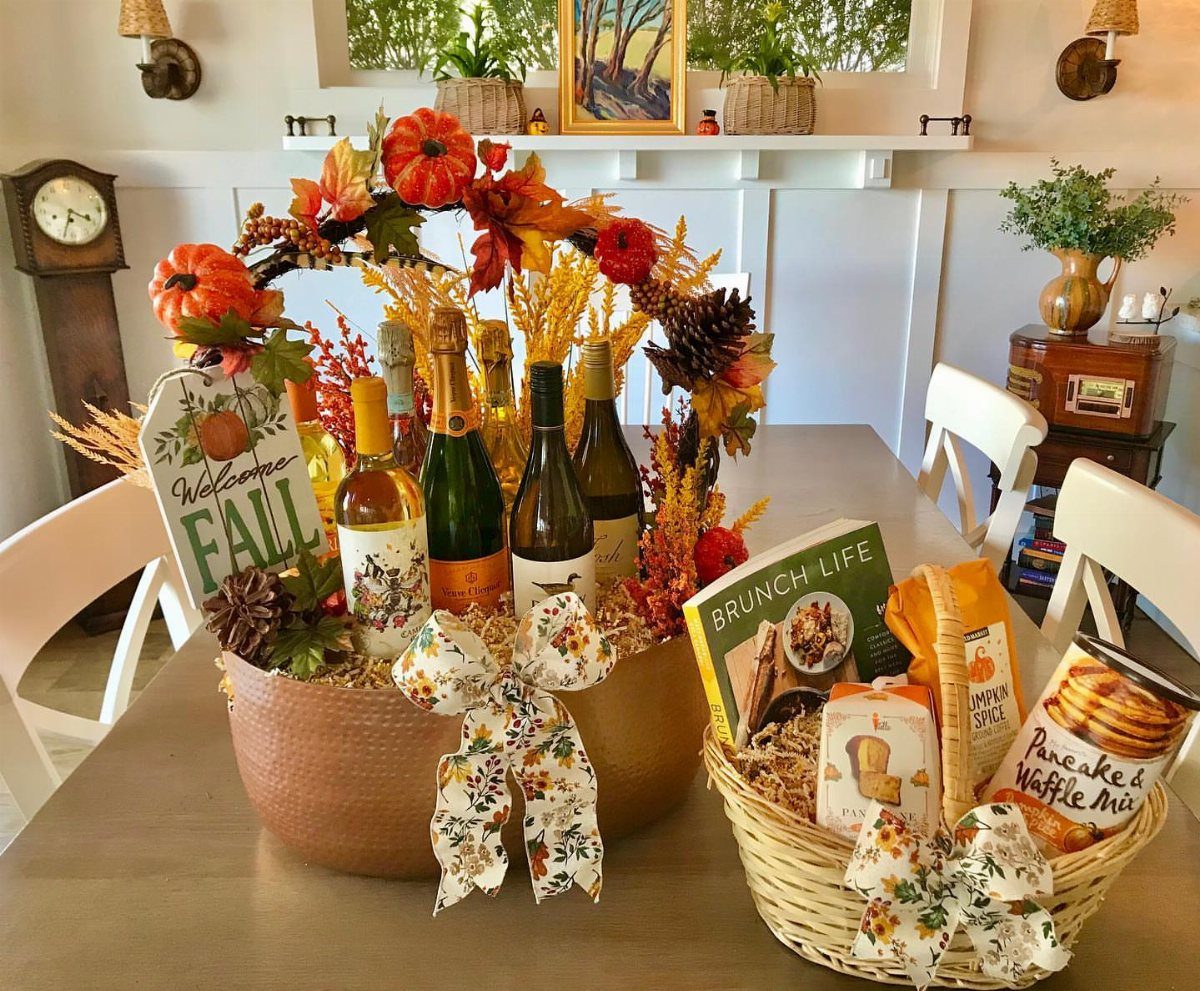 Wine and brunch gift baskets decorated with autumn leaves and floral bows.