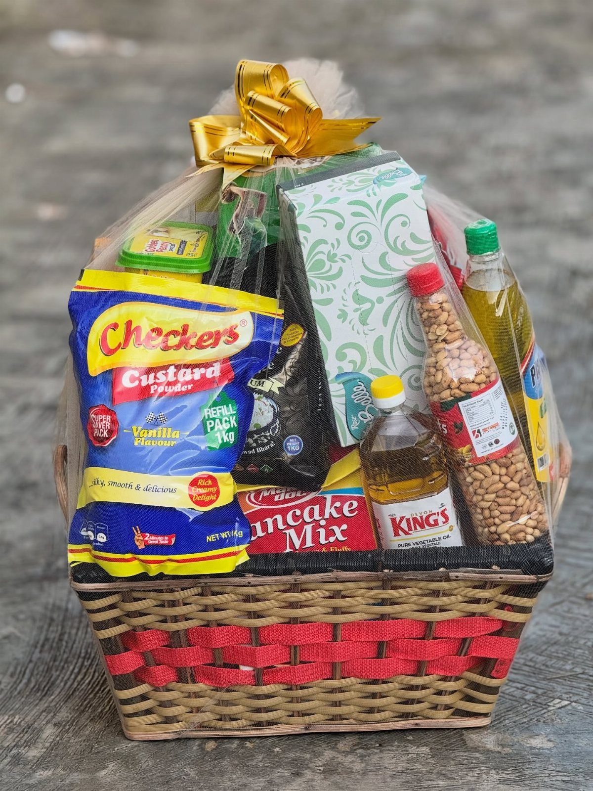 Woven gift basket filled with pancake mix and breakfast items wrapped in cellophane.
