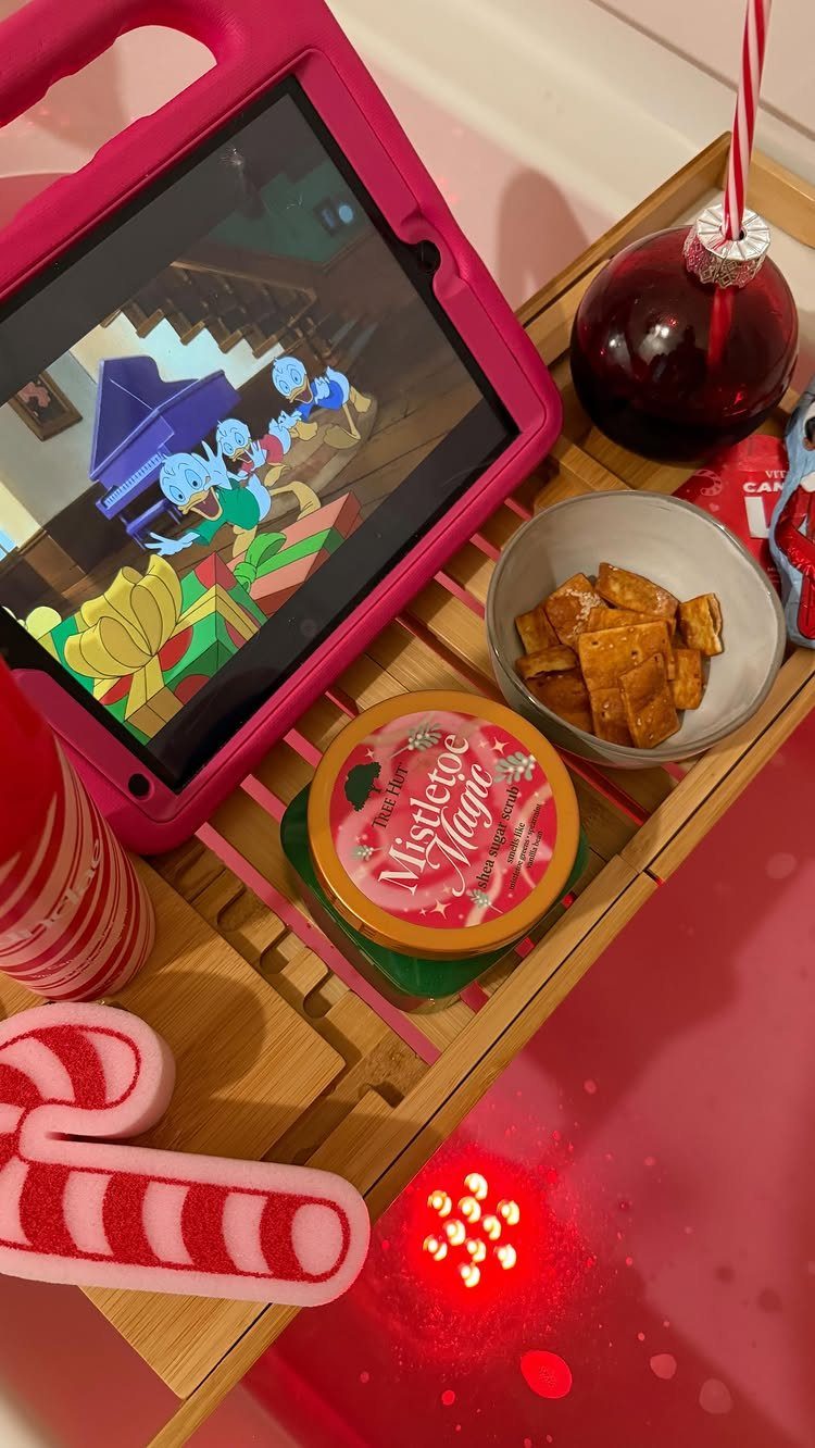 Wooden tray with a tablet playing a movie, snacks, and Christmas treats.