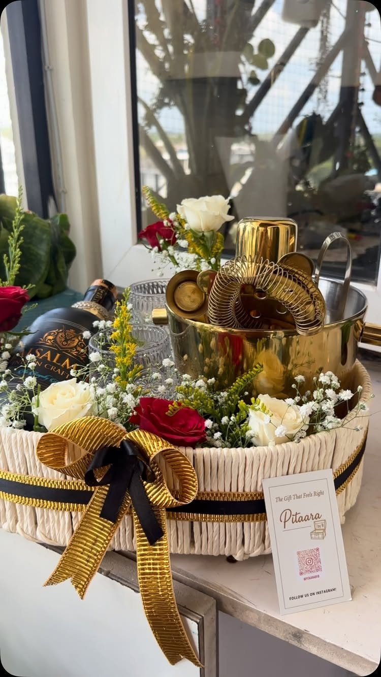 Gift basket with gold cocktail shaker, alcohol bottle, and fresh red and white roses.